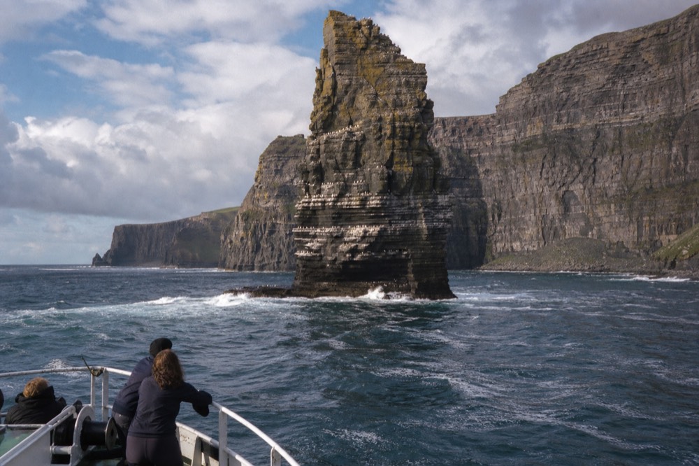 The An Branan Mor sea stack rising sheer from the ocean at the foot of the cliffs, its ledges white with nesting seabirds, the main cliff wall behind.